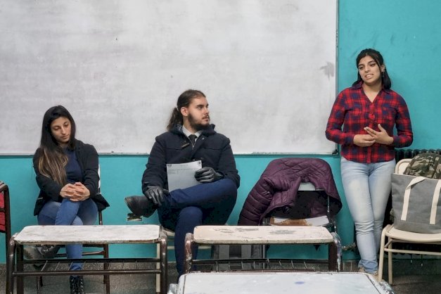 En la imagen se puede ver a  tres integrantes del PEA dando una charla en un colegio de Ushuaia
